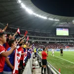 Exciting bóng đá 1gom match scene with fans cheering and players in action at a packed stadium.